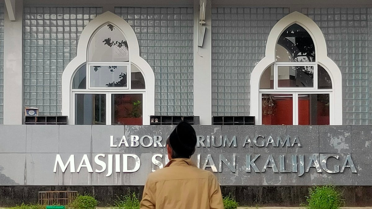 Man in front of a building with arabic writing
